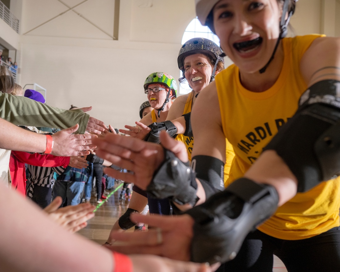 Roller derby team members high-five while facing the camera