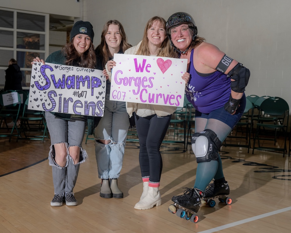 Three fans hold signs supporting the player Gorges Curves while a player poses with them