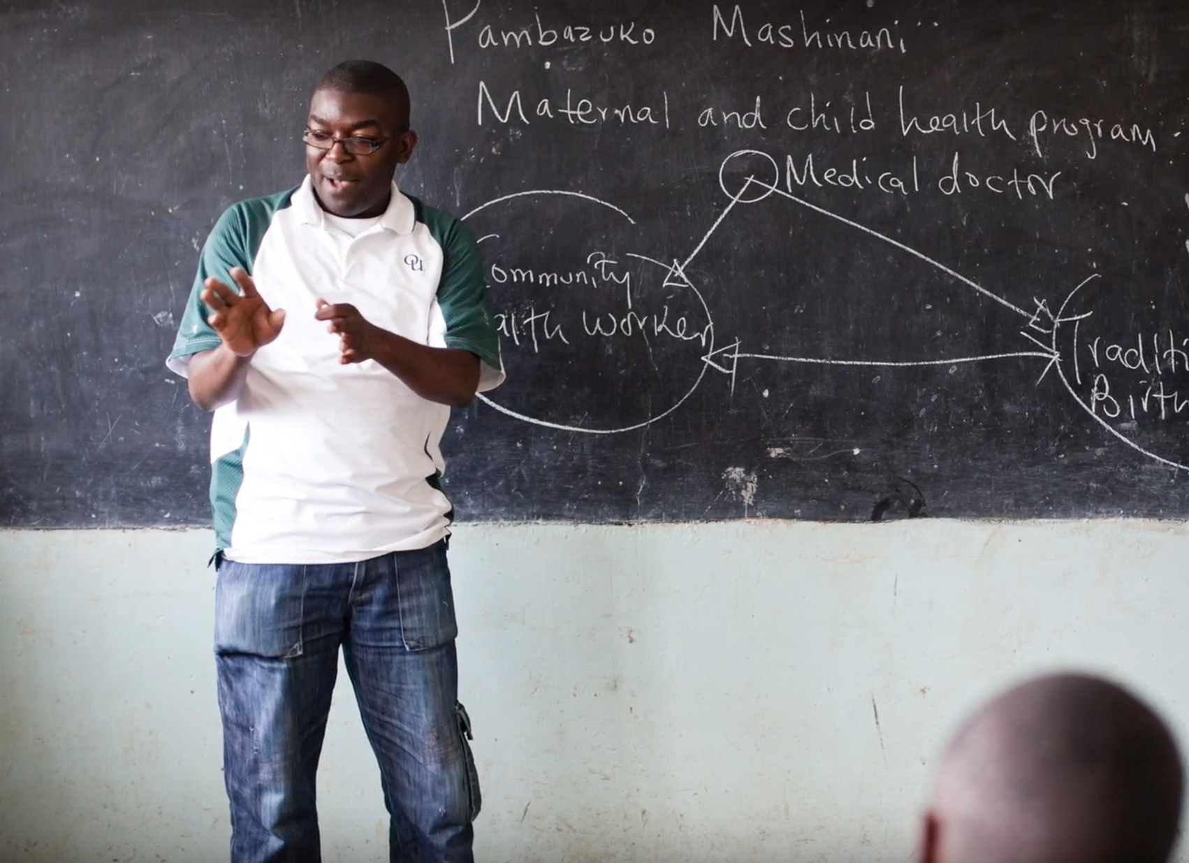 Otieno teaching in front of a chalkboard