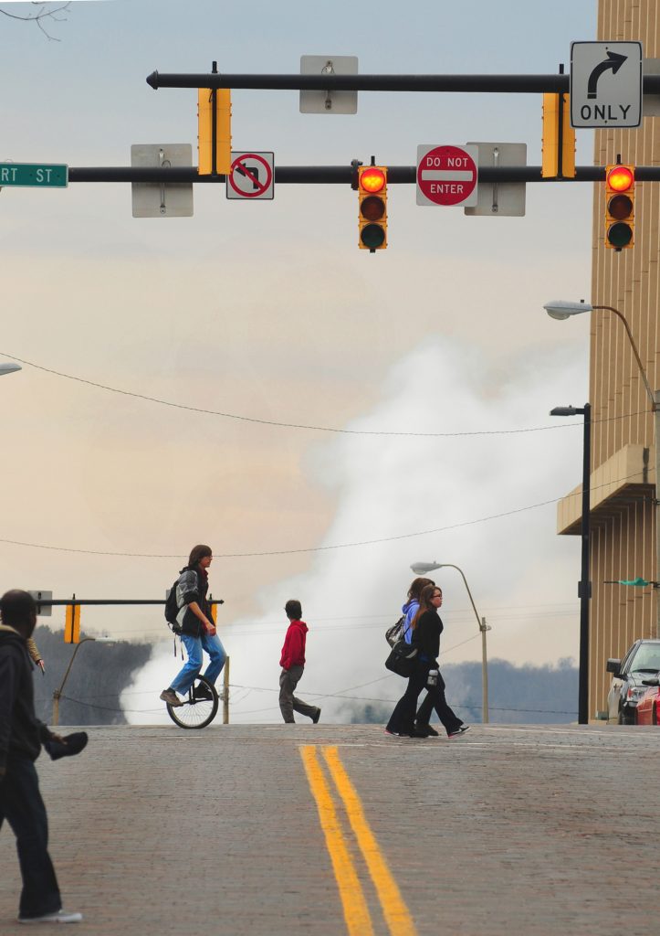 A unicyclist balances on the corner of Union and Court Streets, silhouetted by a West Union Street steam tunnel. While a unicyclist sighting is unusual in many towns, it is not for Athens. 