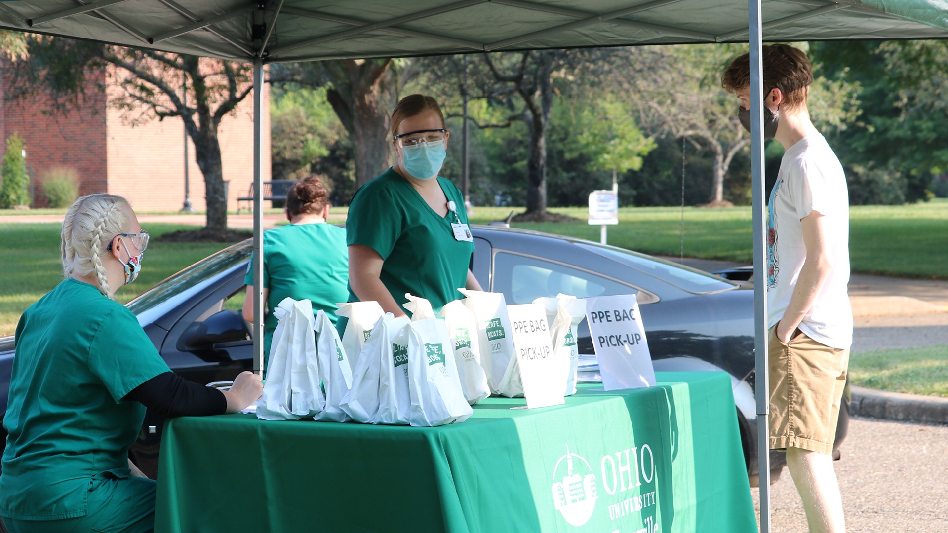 Nurses passing out bags of PPE at a tented location