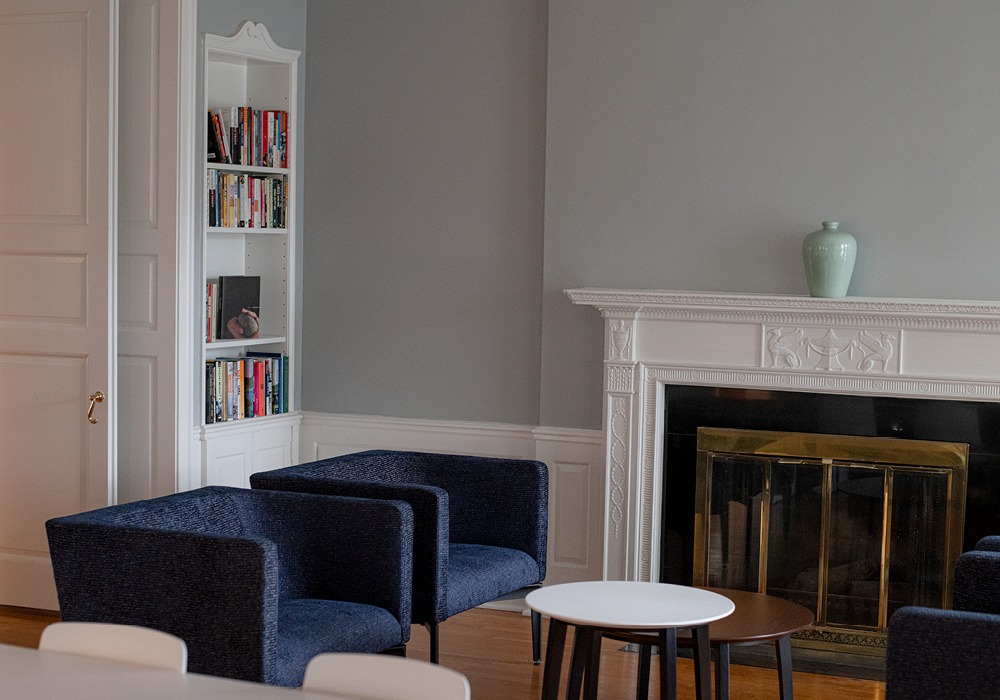 2 chairs in the corner of a room by a book shelf and a fireplace