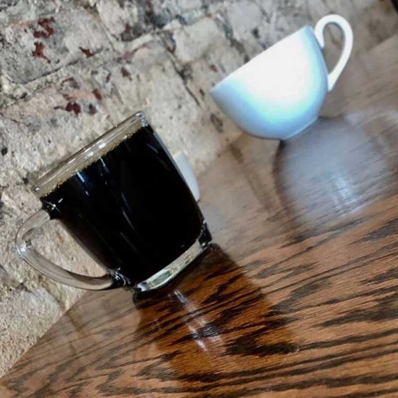 a coffee cup and a tea cup on a table, photographed at a slant