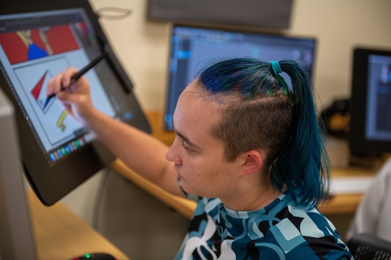 A student works on a computer at the High School Media Workshop