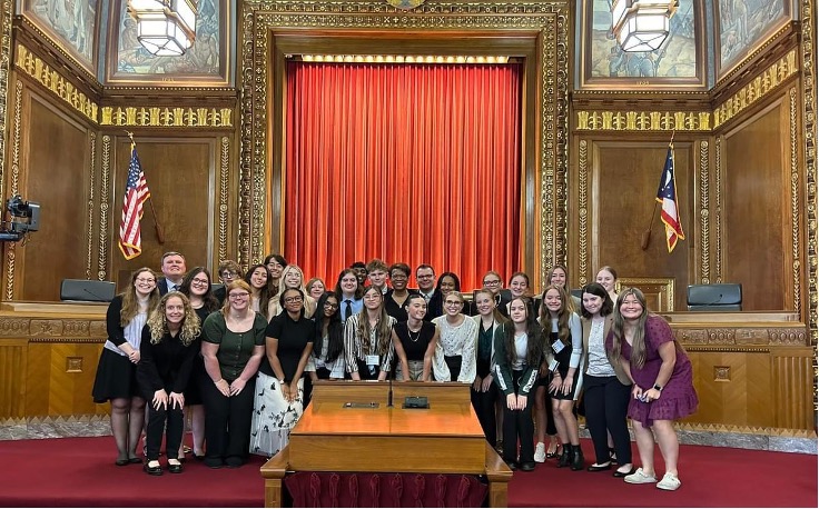 a group of students poses in a wood-paneled courtroom, flanked by the U.S. and Ohio flags