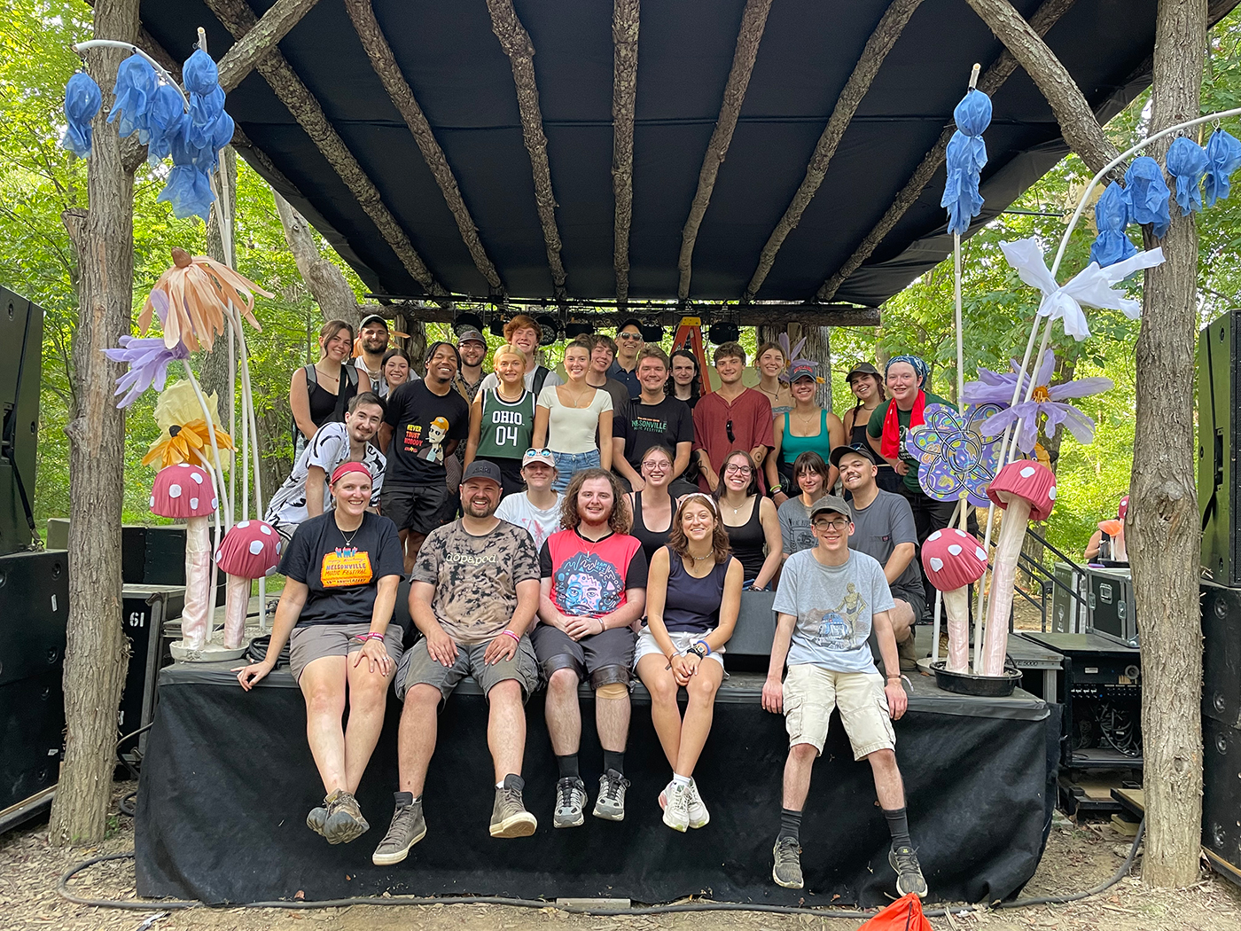 Ohio University faculty and students from the School of Media Arts and Studies pose with staff from OHD Studios on Nelsonville Music Festival's Creekside Stage.