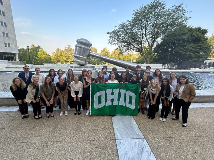 A group of high school students pose in front of a fountain with a giant gavel sculpture