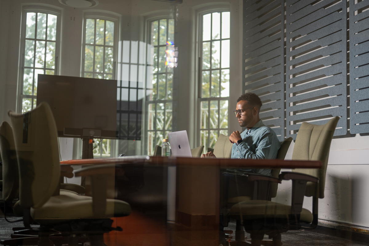 A student studies in an office setting with his laptop. 