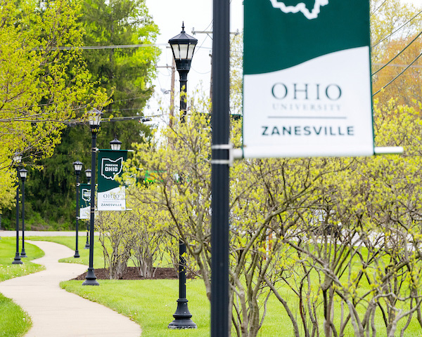 A walkway on the OHIO Zanesville campus with trees and signage.