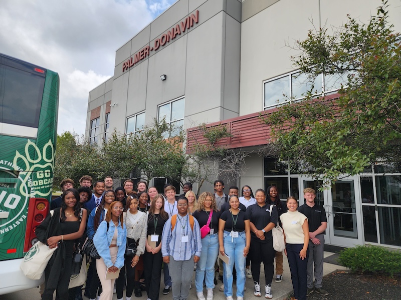 A group of students poses for a photo outside the offices of Palmer-Donavin