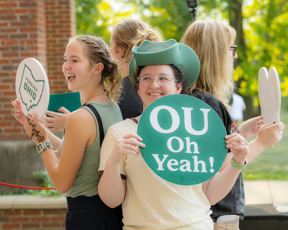 Students stand back-to-back posing for a picture, holding 