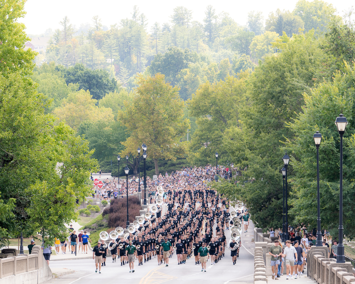 the Marching 110 leads a large group of students up Richland Avenue bridge