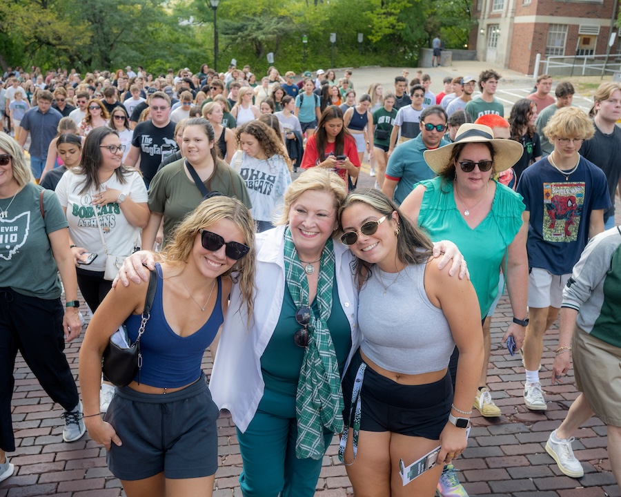 President Gonzalez walks up Richland Avenue with her arms around two students