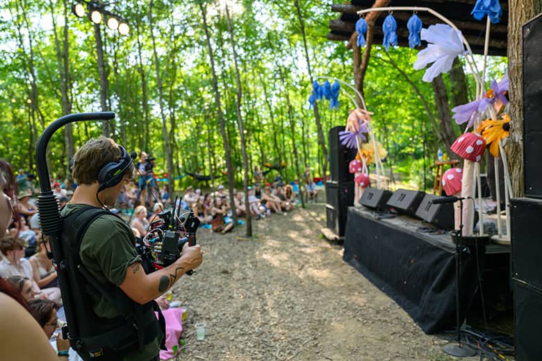 An OHIO student operates a camera with a weighted gimbal to record stable footage of the Creekside Stage.