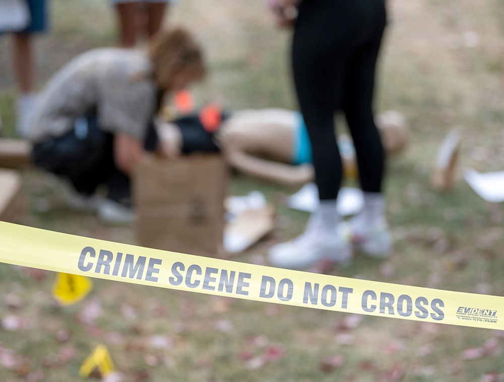 Students at Ohio University work on a mock crime scene behind yellow tape labeled "Crime scene do not cross"