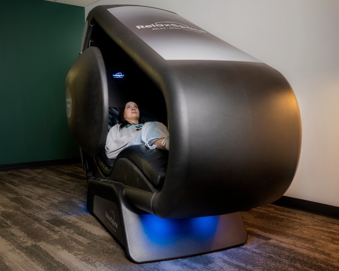 A student reclines in a large pod 