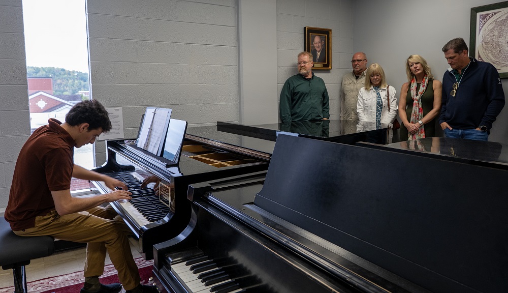 OHIO student Alejandro Orta plays the piano while family members and friends watch in Glidden Hall