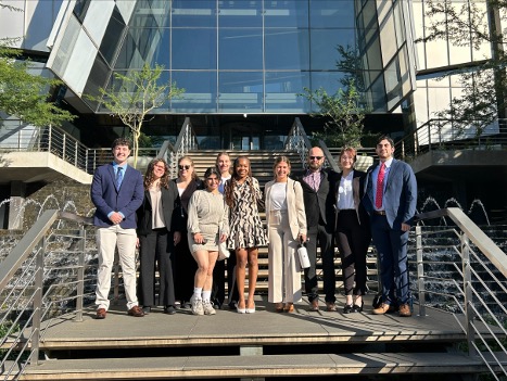 Group of people pose for a picture in front of a glass building