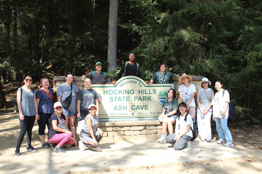 A group poses for a photo with the Ash Cave sign in the Hocking Hills