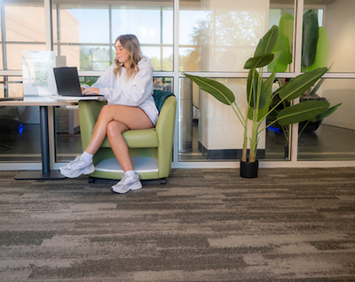 A student in a green chair works on a laptop