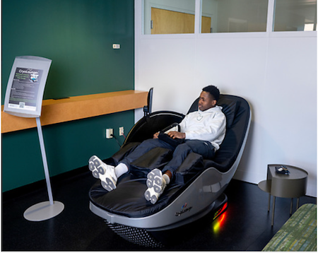 a student reclines in a futuristic-looking reclining chair