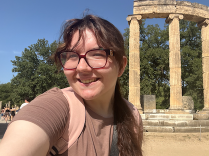 Student poses in front of ancient ruins in Greece