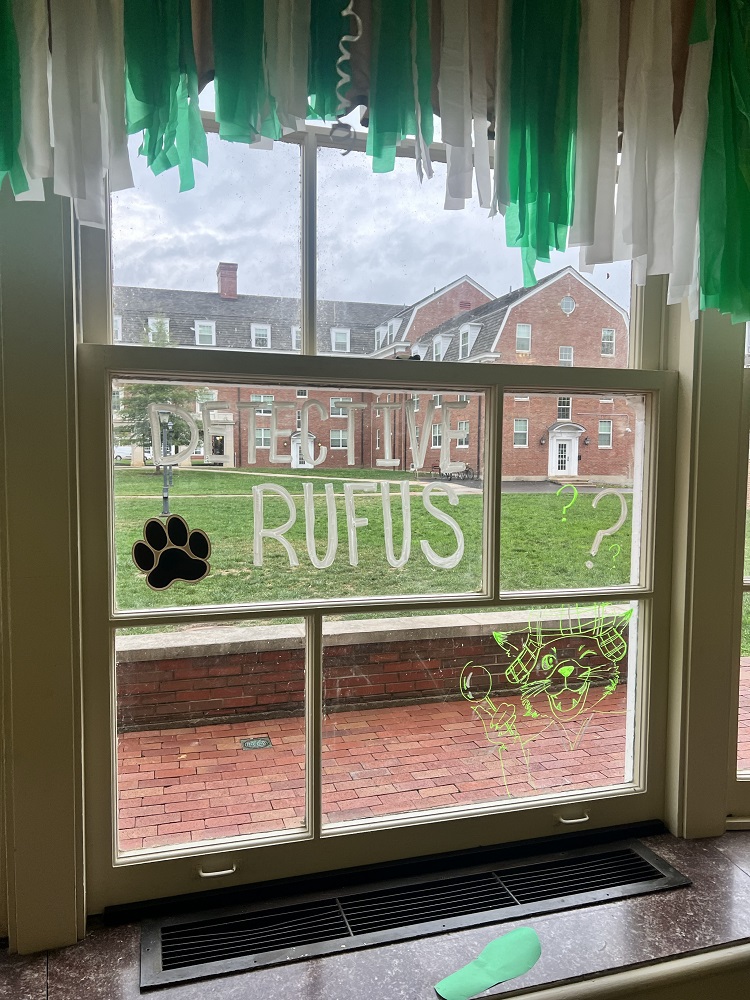 A window has green and white streamers on it and paint on the window says 