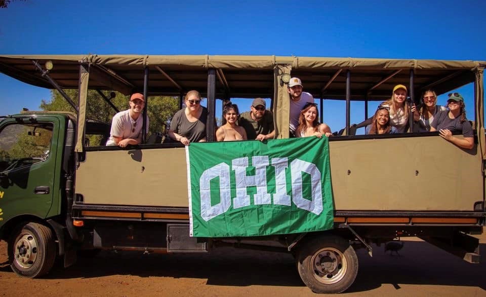 group of people posing in a safari van holding a OHIO flag