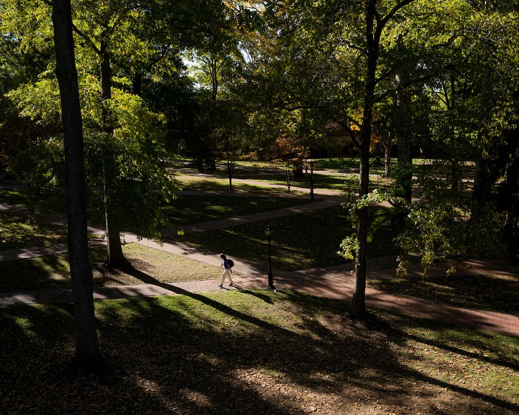 A student walks across Ohio University's College Green on a Fall day