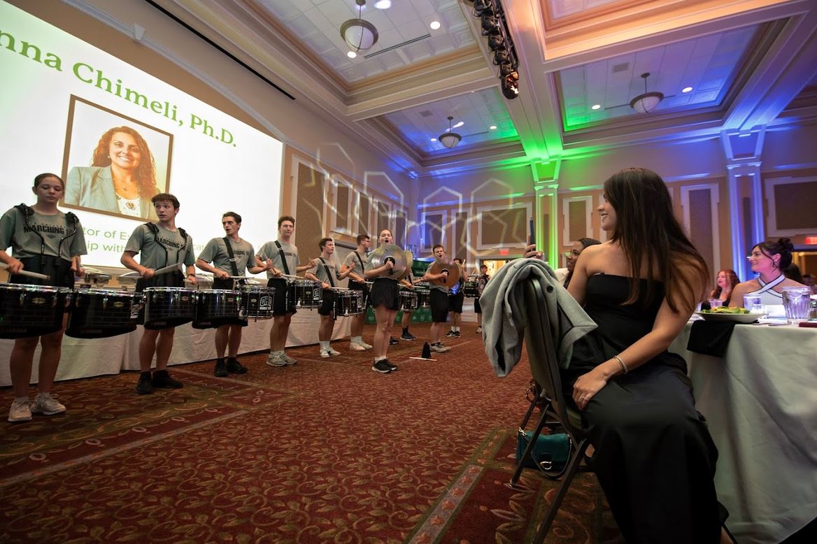 A marching band preforming in front of sitting viewers at Baker Ballroom.