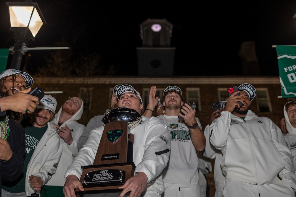 OHIO football players celebrate on College Green, holding the MAC Championship trophy