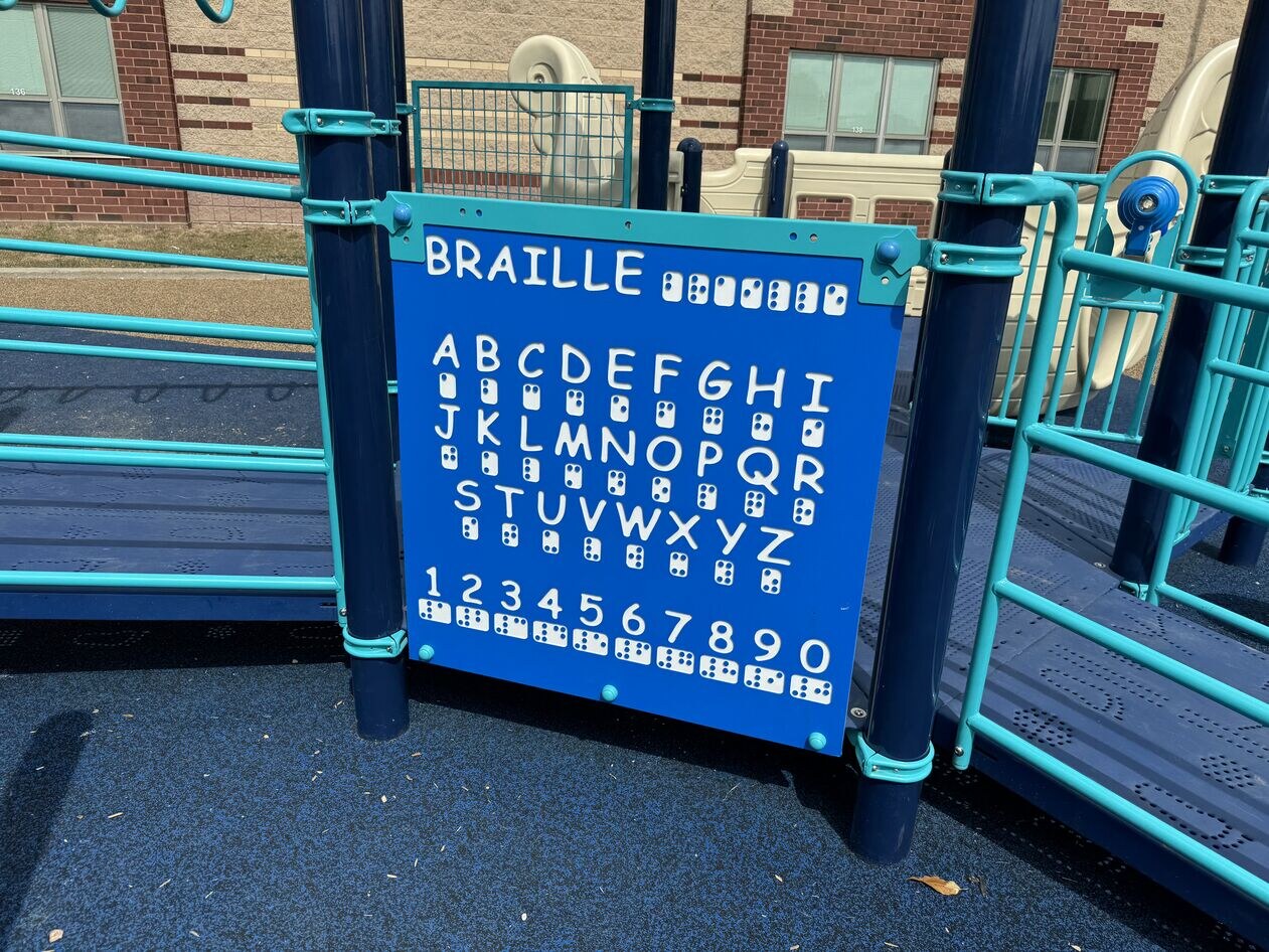 Section of playground including a board depicting the braille alphabet