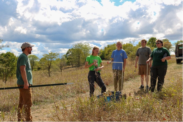 Students stand in a field holding fencing