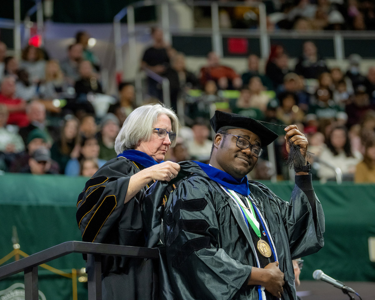 Professor Sarah Wyatt bestows an honor to a graduate at the Fall 2024 commencement ceremony