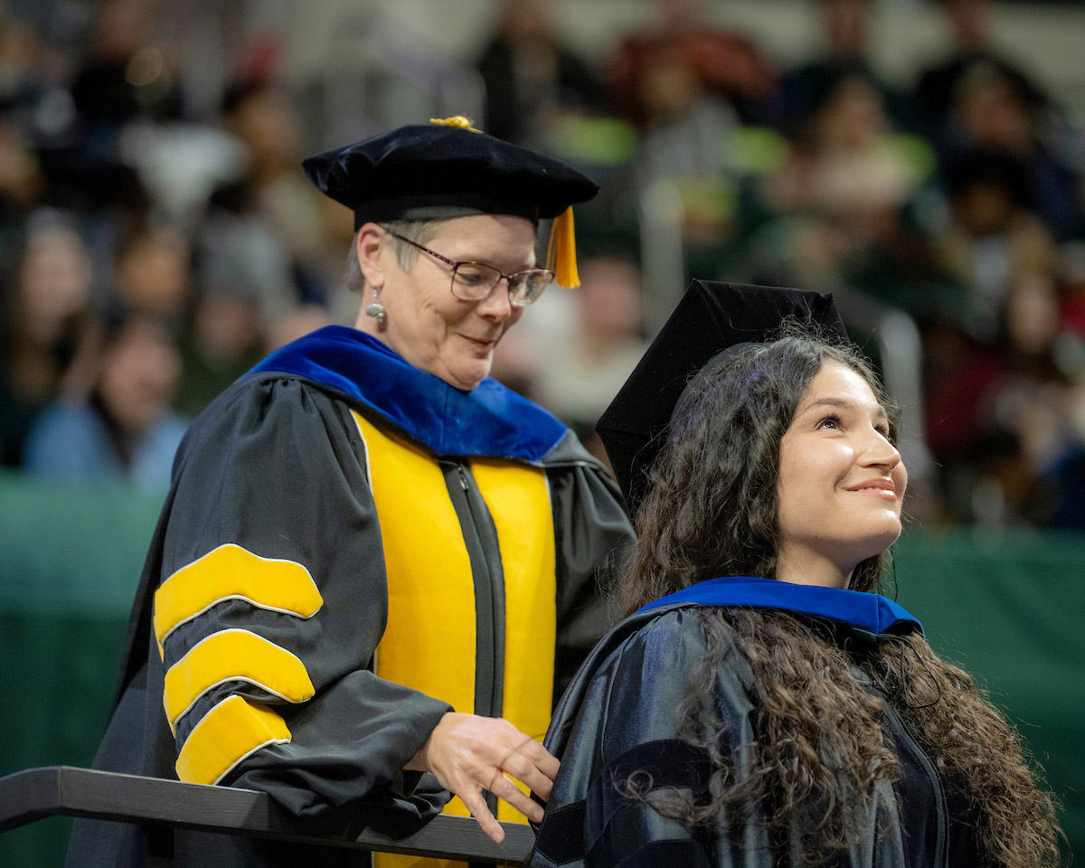 A graduating student receives an honor on stage at the Fall 2024 commencement ceremony