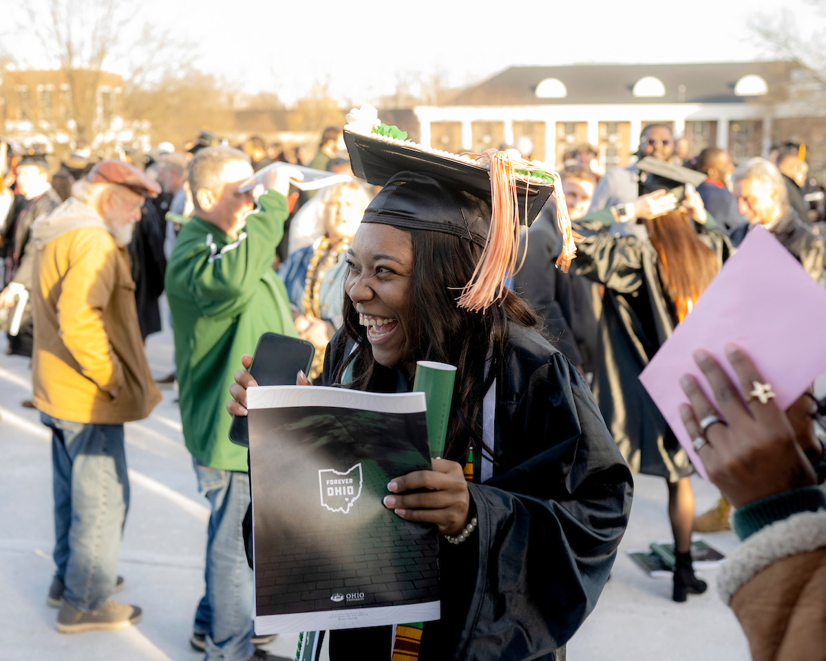 A graduate cheers to a supporter following the Fall 2024 commencement ceremony