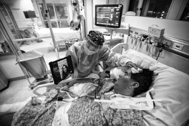 Black and white image of hospital bed with medical professional tending to a patient