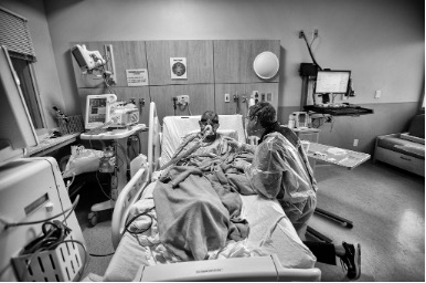 Black and white image of hospital bed with medical professional tending to a patient