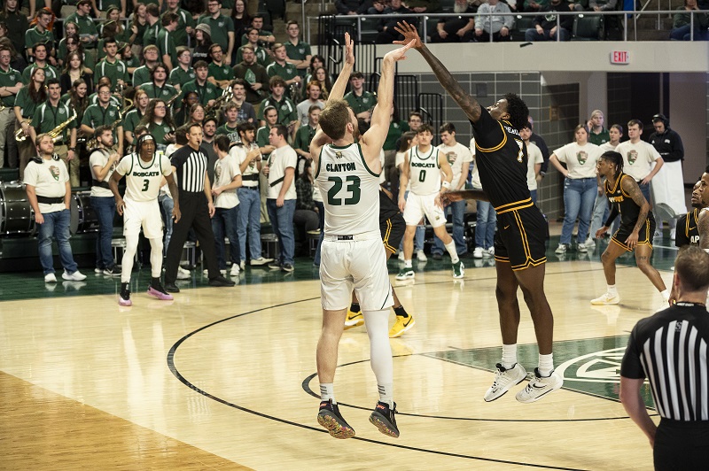 An OHIO Men's Basketball player shoots a three-point shot in front of a large crowd in the Convocation Center