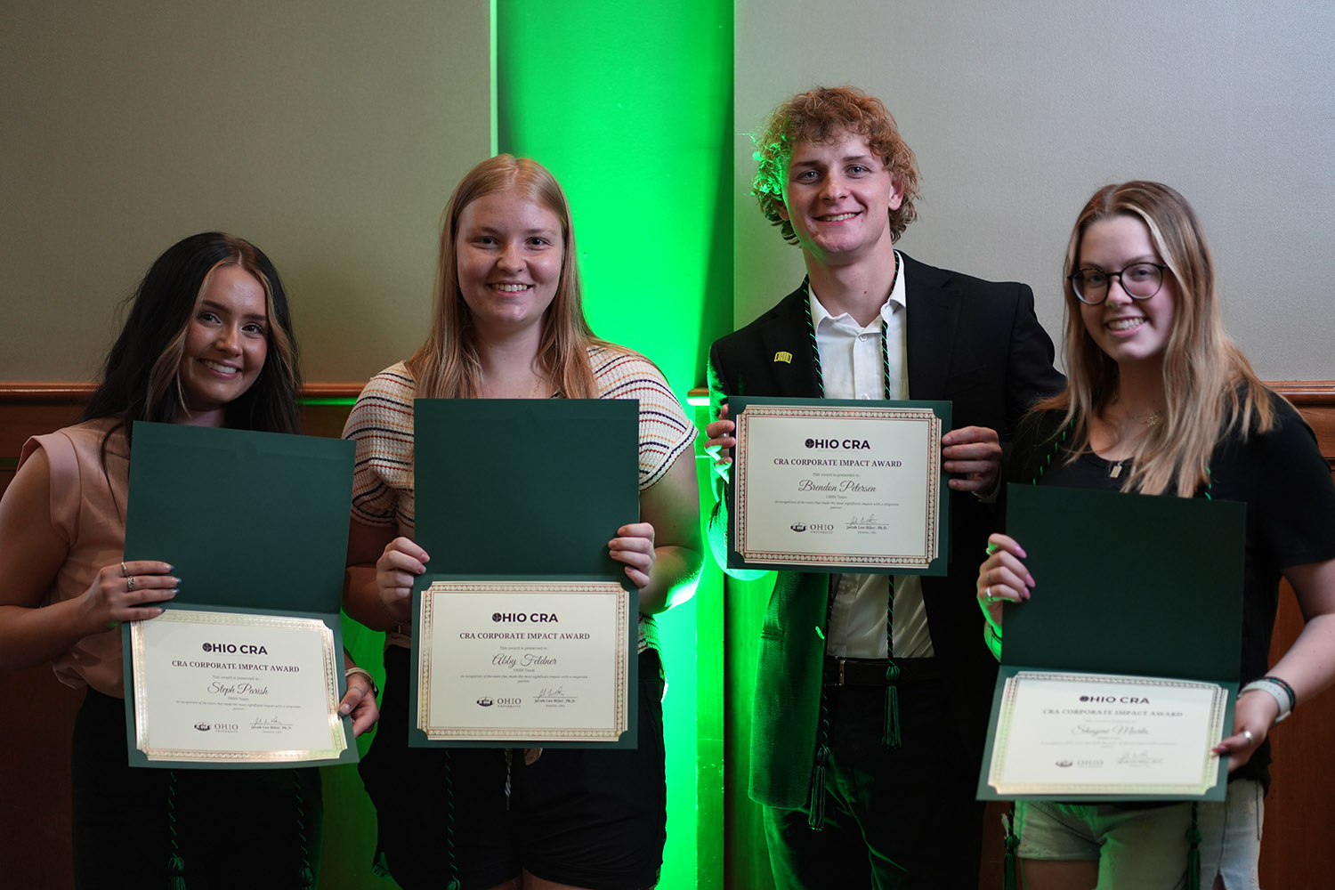 four students hold certificates they earned for their work in the CRA