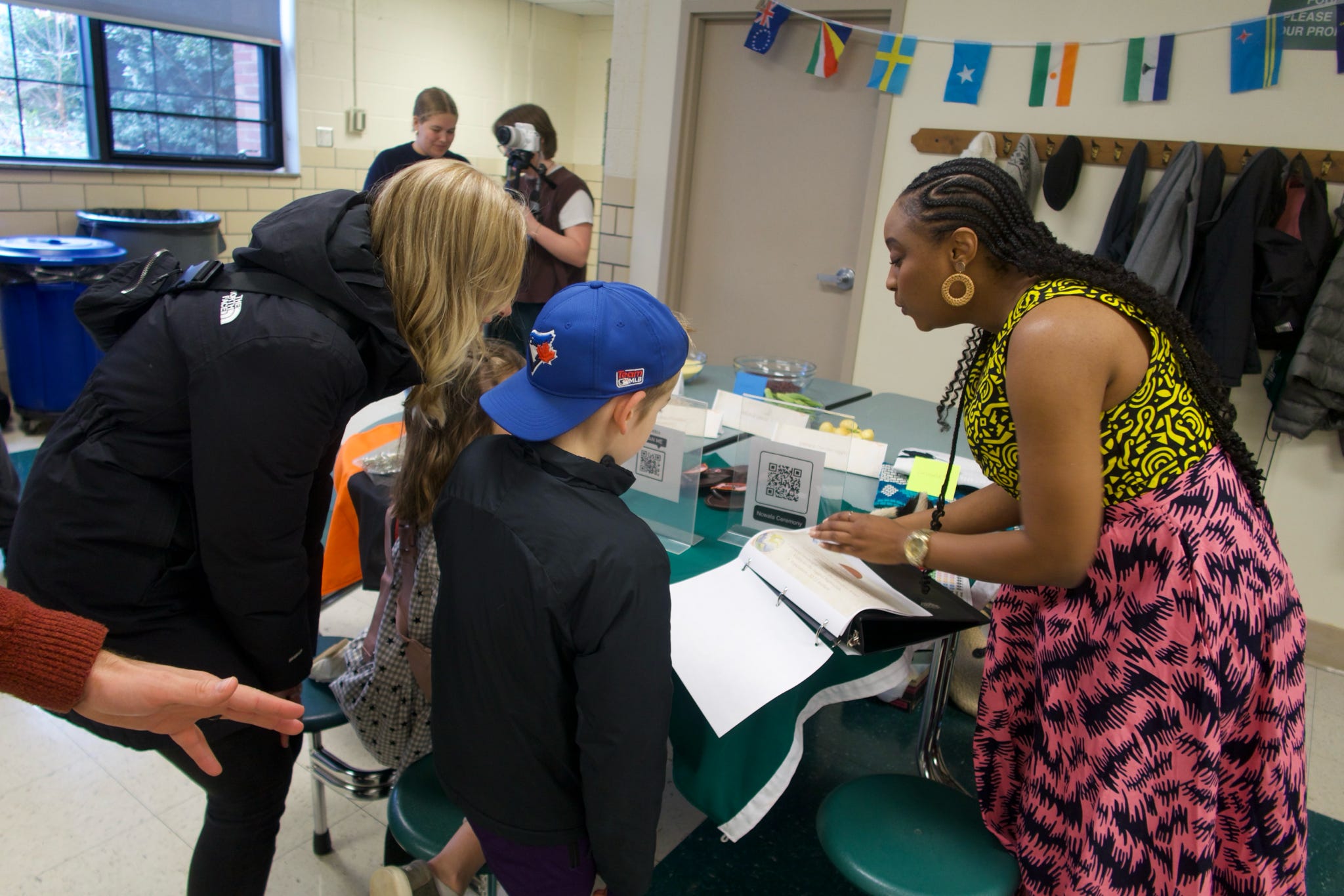 A group of adults and children huddling around a table in a school.