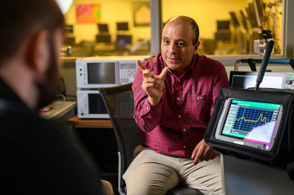 A man sitting down surrounded by monitors and technology.