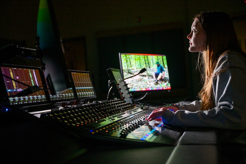 An OHIO student runs audio/video production equipment in a dark room