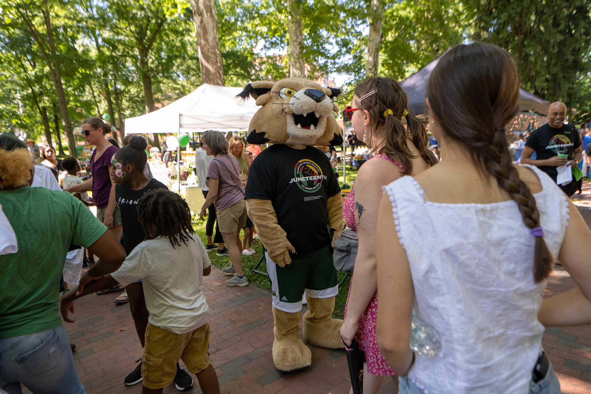 Community members explore the Juneteenth event on College Green alongside Rufus the Bobcat.
