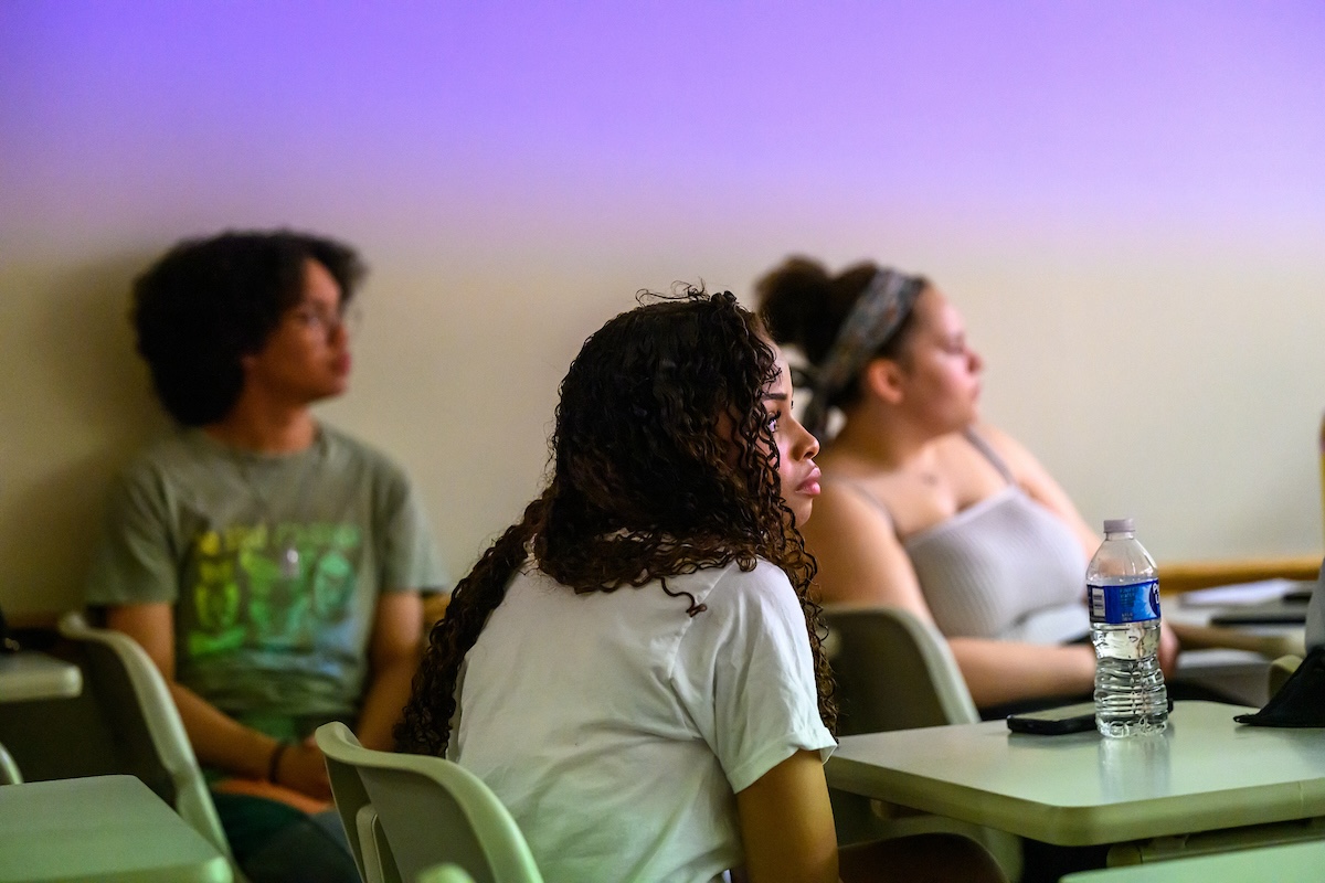 Students sit in a classroom attentively gazing in the same direction