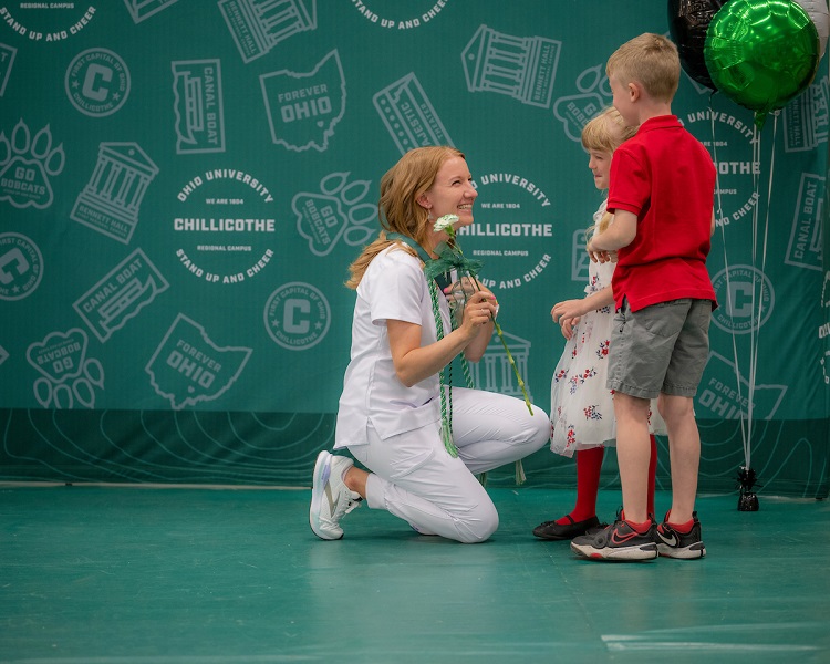 An OHIO student celebrates with two small children after the Nurses Pinning Ceremony at OHIO Chillicothe