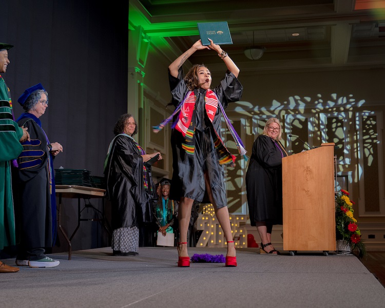 An OHIO student celebrates her graduation while walking across the stage