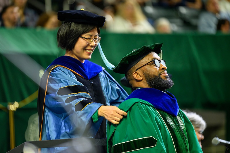 An OHIO PhD student receives his stole from an OHIO faculty member at Spring Commencement
