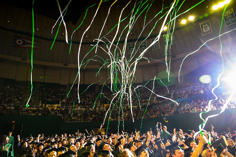 Green and white streamers fall from the Convocation Center ceiling over the graduates at Spring Commencement