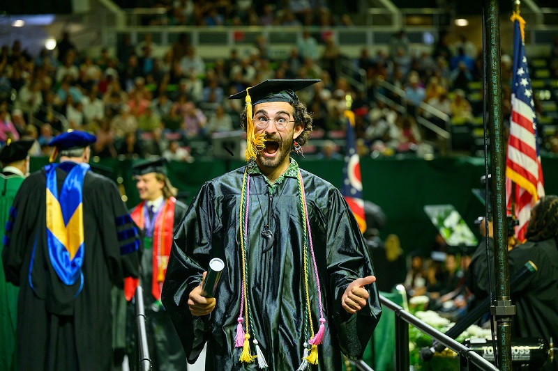 An OHIO student celebrates after crossing the stage at Spring Commencement in the Convocation Center